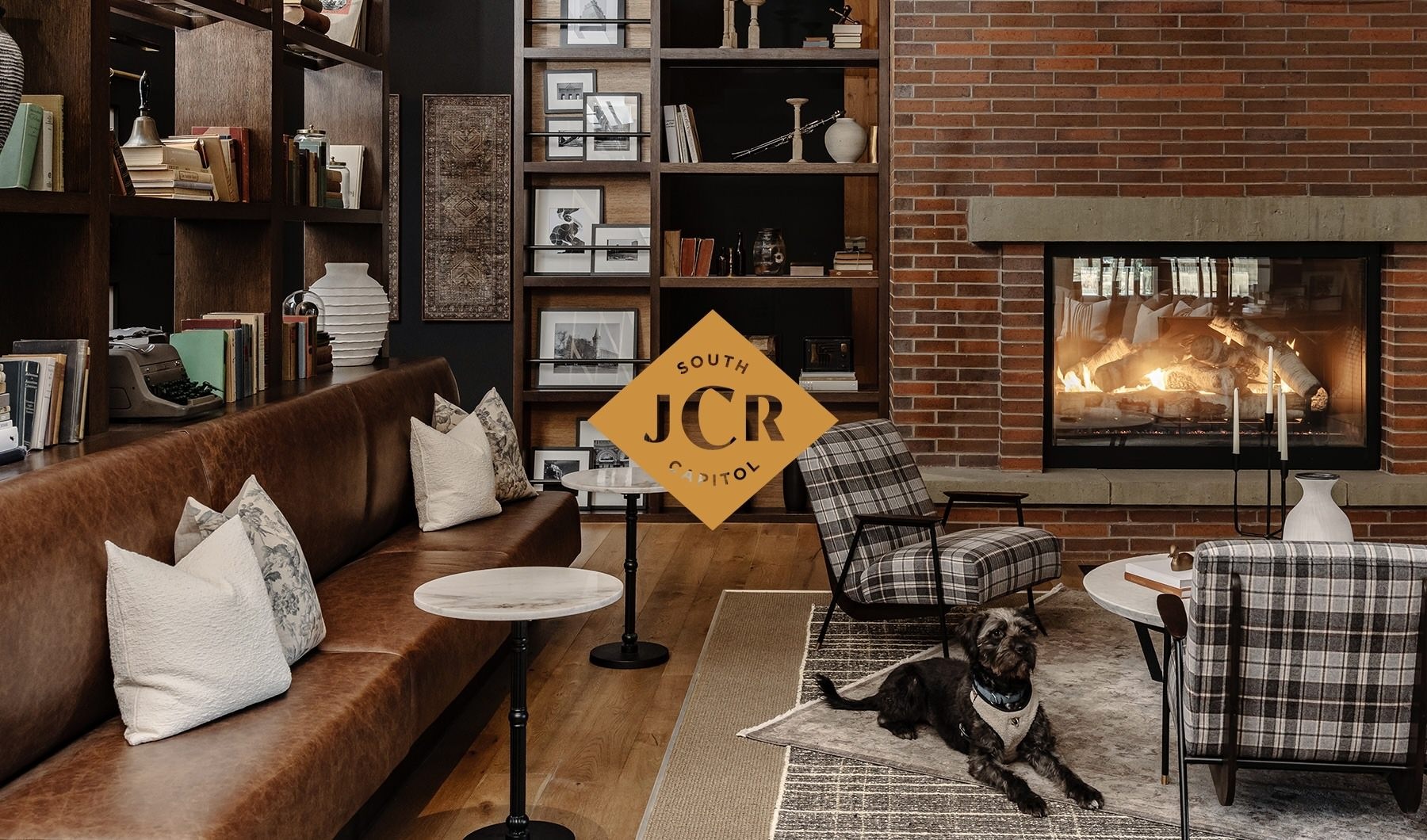 Luxury Apartments Southwest DC lobby lounge with leather benches, plaid armchairs and brick fireplace with warm fire